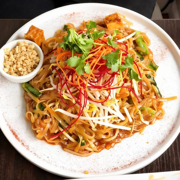 Vegan Pad Thai with noodles, tofu, bean sprouts, shredded carrots, red cabbage, and cilantro.